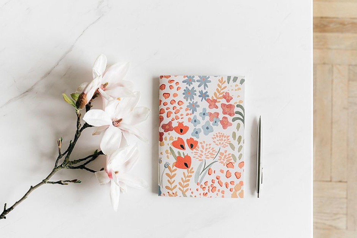 Small notebook beside flowers on a bright table prepared for reading